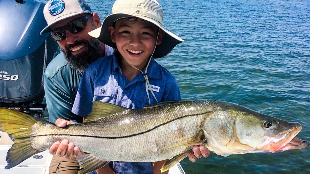 a sarasota fishing guide helping a child hold a fish they caught