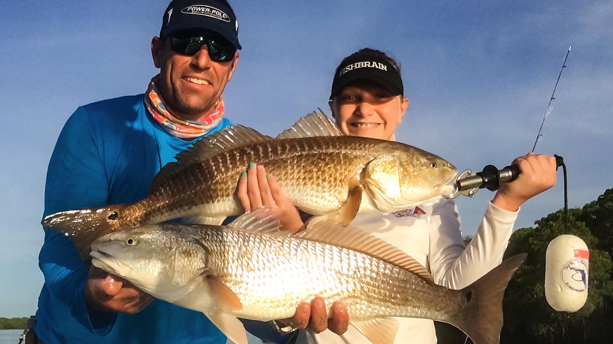 a bradenton fishing guide and a client holding redfish they caught