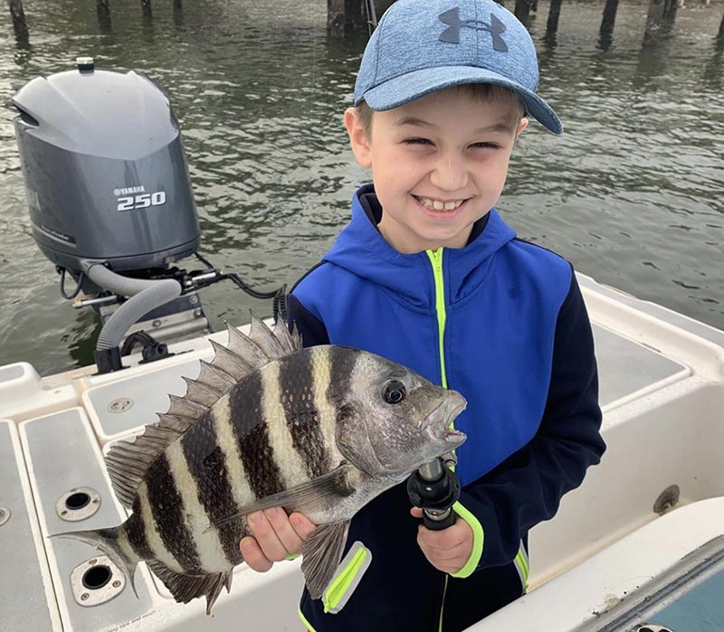 a picture of a young boy holding a sheepshead he caught while on a family friendly fishing charter with Capt. Nate.