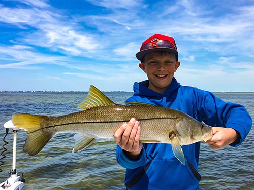 a picture of a child holding a snook he caught while on a family friendly fishing trip with Capt. Nate